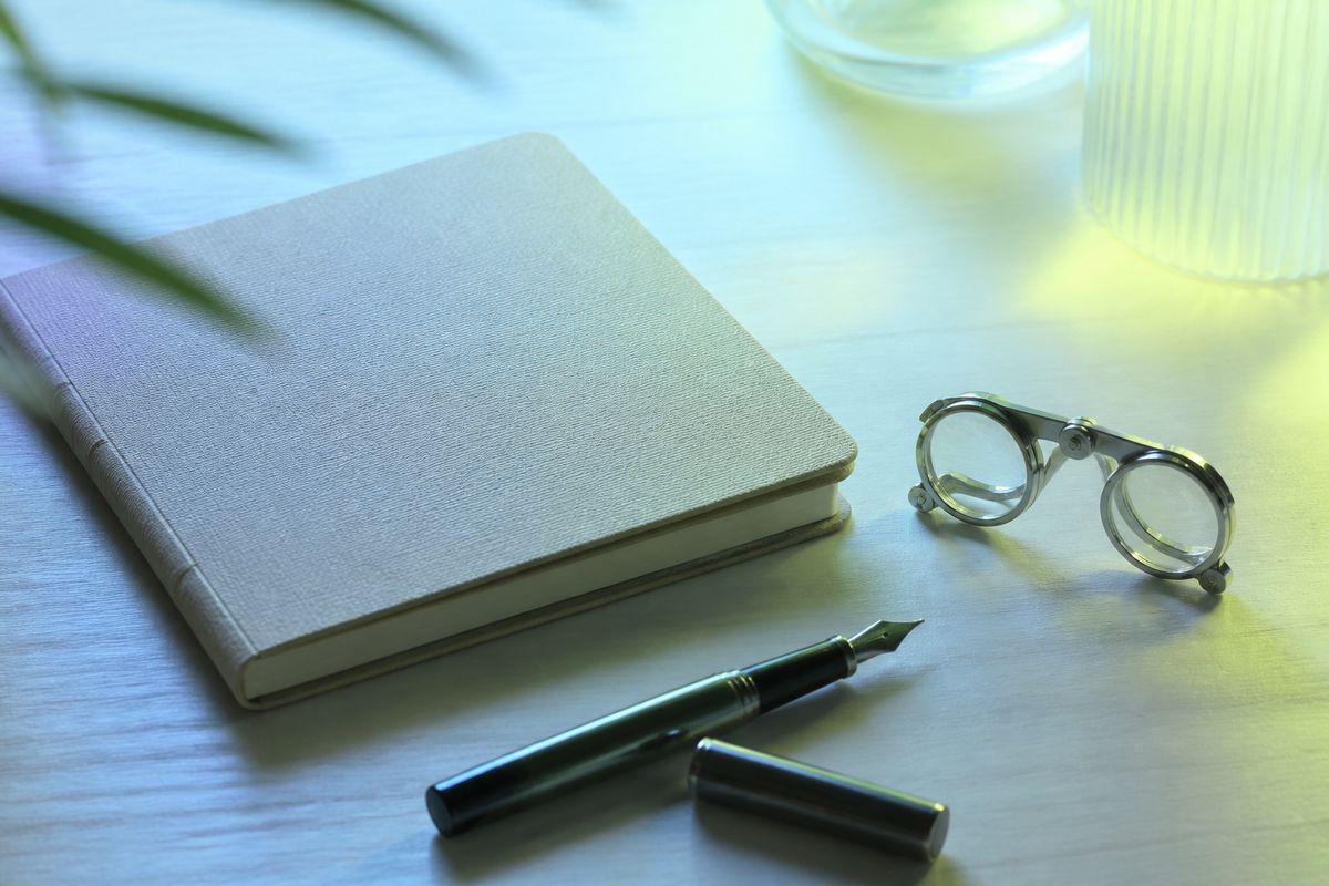 Notebook and pen on a light desk suggesting editorial review work